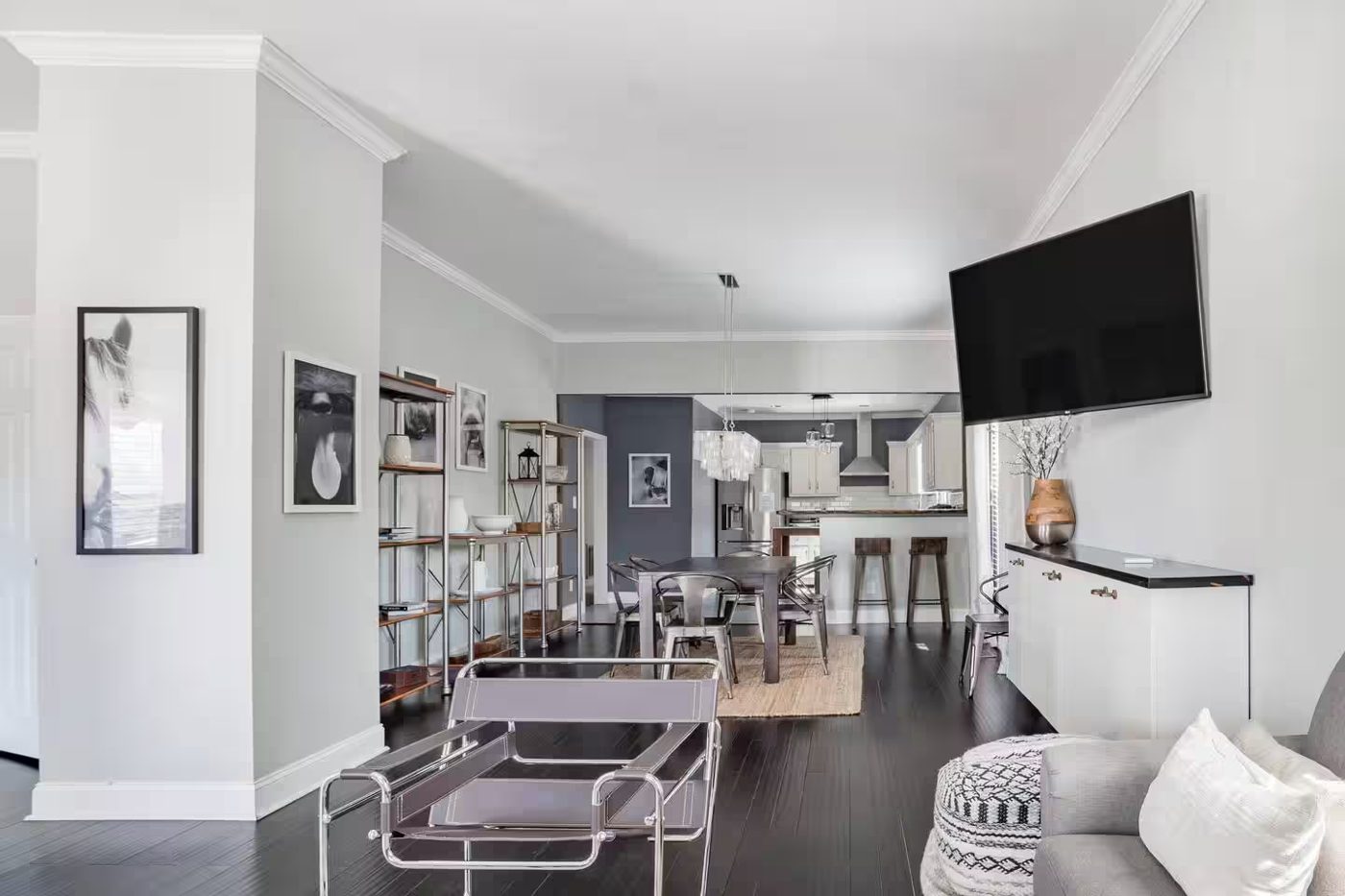 Open-plan living and dining space in black, white, and gray with a chrome sling chair and metal shelving